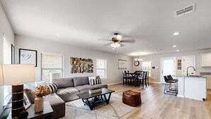A spacious living room with a sofa, coffee table, and a dining area with chairs and a table.