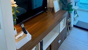 Ein modernes Wohnzimmer mit Flachbildfernseher, einer Holzunterhaltungsecke und Blick ins Freie.