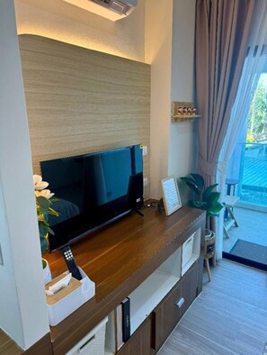 Ein modernes Wohnzimmer mit Flachbildfernseher, einer Holzunterhaltungsecke und Blick ins Freie.