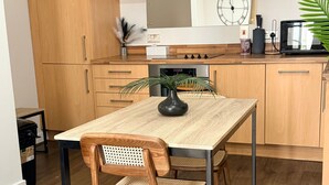 A modern kitchen with wooden cabinets, a dining table, chairs, a microwave, and a clock on the wall. - One Bedroom Flat in Mailbox With Free Parking (Birmingham)