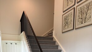 A staircase with a checkered carpet, black railing, and white walls with framed artwork. - Charming 1-bedroom studio cottage in delightful Fish Haven with AC (Fish Haven)