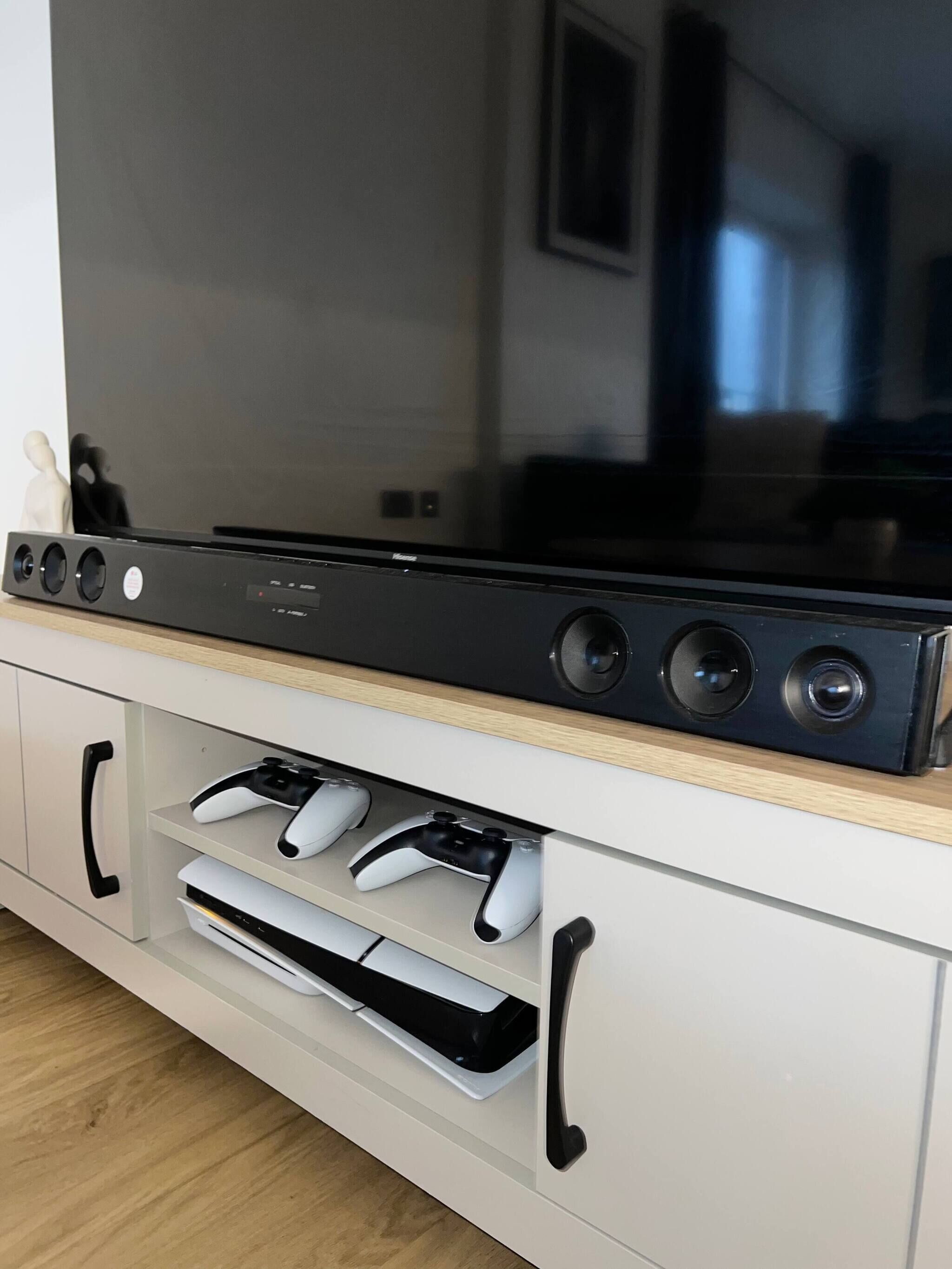 Una TV a schermo piatto montata su un mobile bianco con due joystick e un lettore DVD.