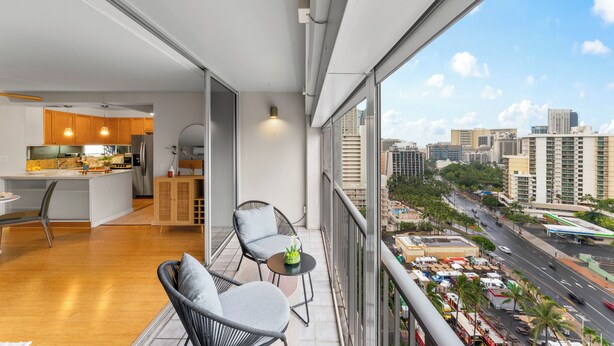 Un balcón con vistas a la ciudad, una zona de cocina y asientos.