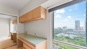 Una cocina moderna con armarios de madera, encimera de vidrio y un amplio ventanal con vista a la ciudad.
