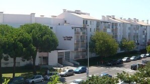 A multi-story residential building with balconies, a parking lot, and trees in front. - T2 cabin for 4 people, terrace, parking near the beach (LE GRAU DU ROI)