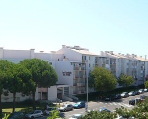 A multi-story residential building with balconies, a parking lot, and trees in front. - T2 cabin for 4 people, terrace, parking near the beach (LE GRAU DU ROI)