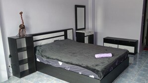 A bedroom with a bed, bedside tables, a mirror, a fan, and a giraffe decoration. - Old Town (Pattaya)