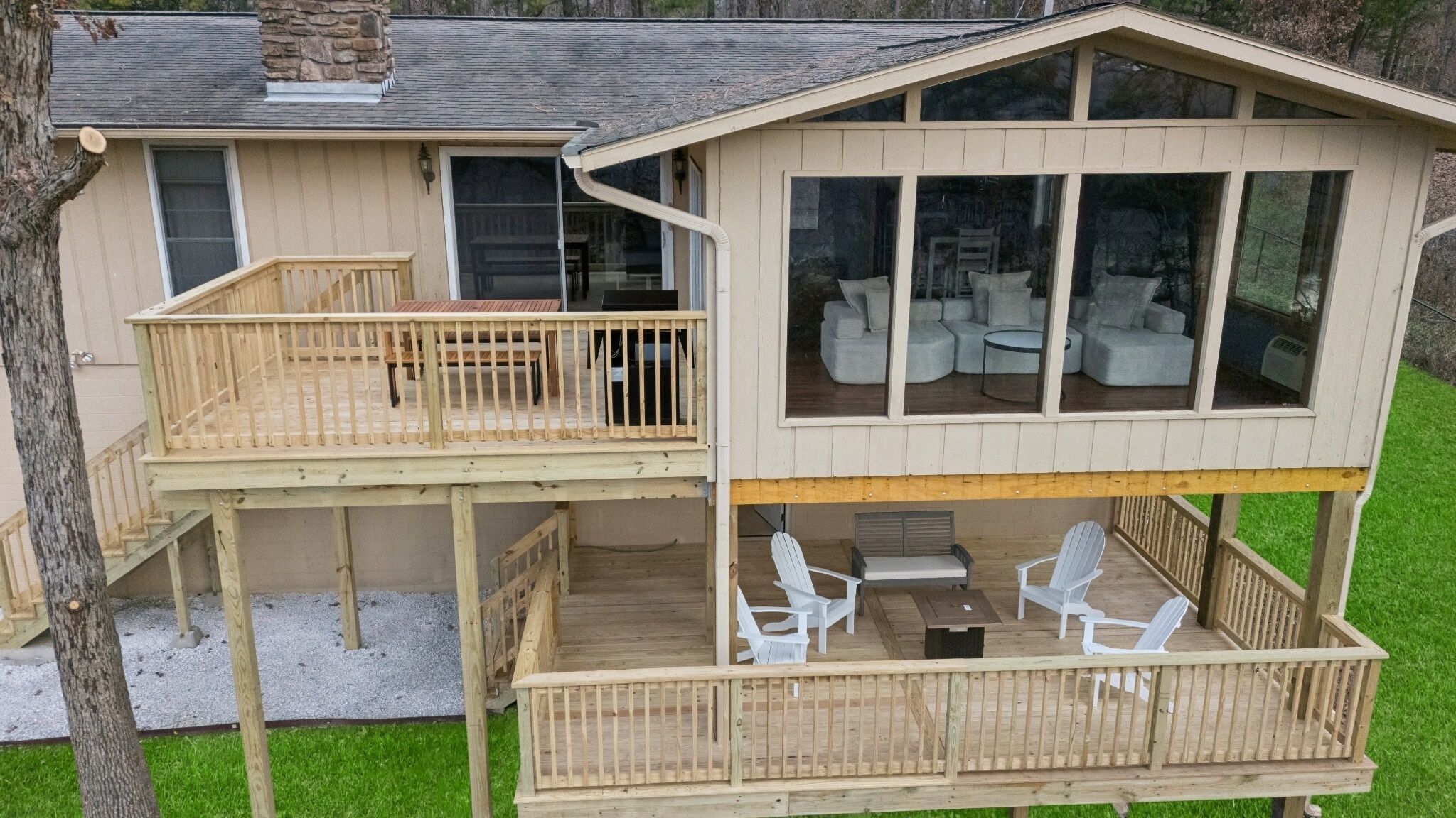 A two-story house with a deck, outdoor seating, and large windows.
