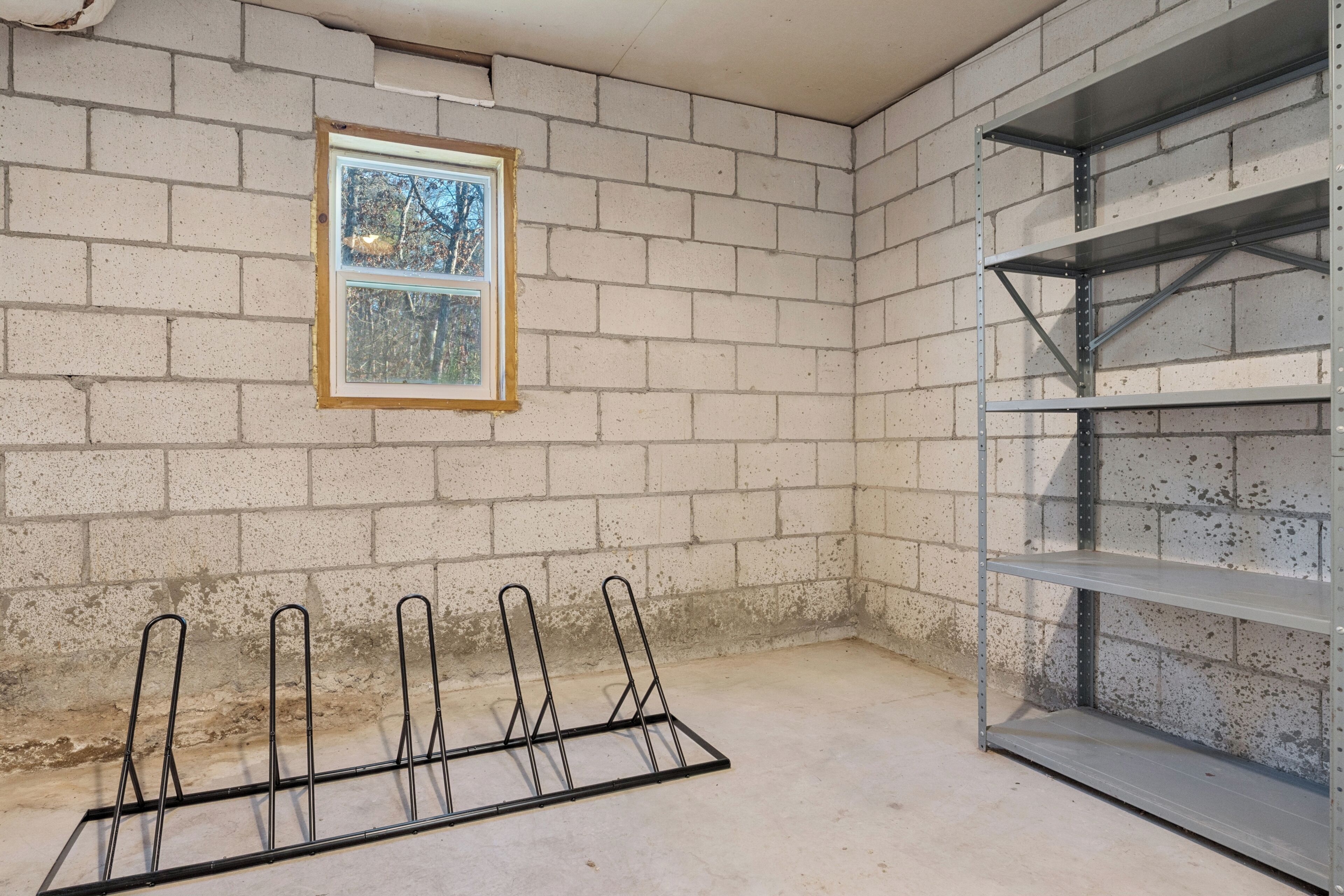 A room with a brick wall, a window, and metal shelving units.