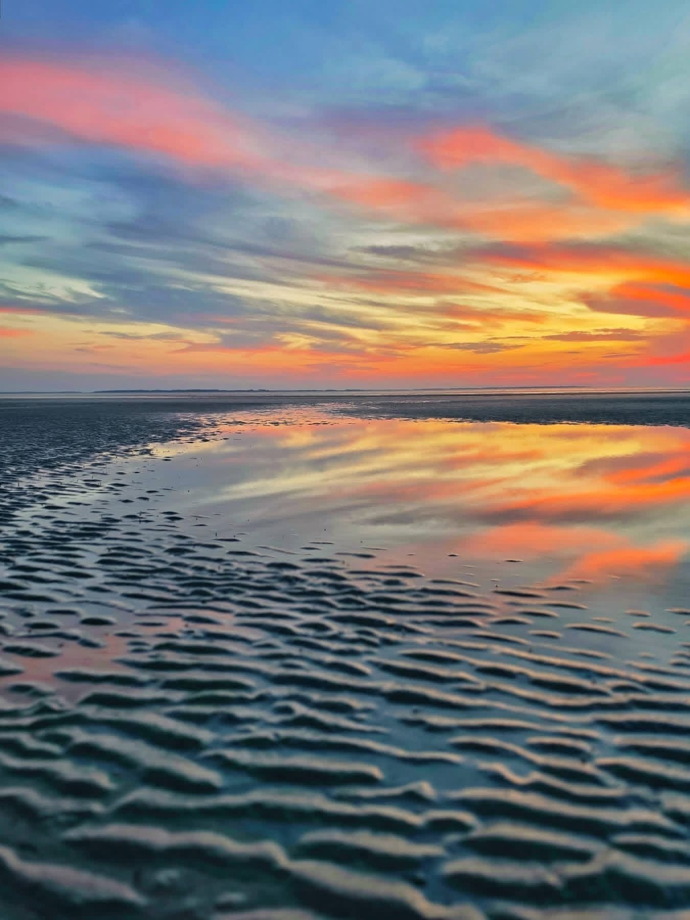 Ein Strand mit ruhigem Meer und einem Sonnenuntergangshimmel.