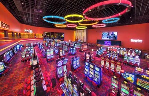A casino with multiple gaming machines, a stage area, and a large screen displaying a game. - Large Private Villa with Pool, Sauna, Billiards, Minutes from the Beach (Dania Beach)