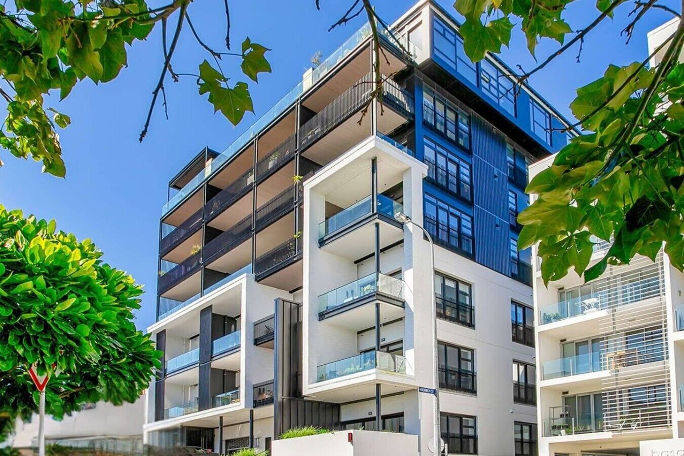 Un edificio residencial de varios pisos con balcones, ventanas amplias y cielo despejado.