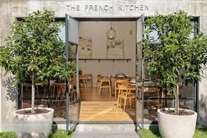 A restaurant entrance with a sign reading 'The French Kitchen,' featuring a modern interior with wooden furniture and potted plants. - Stylish city retreat, coffee machine, balcony and city views and free carpark! (Auckland)