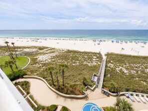 Ein Strandresort mit gepflastertem Weg, Palmen und Strandliegen.