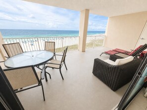 Ein Balkon mit Glastisch und -stühlen, einer Korbschaukel und Blick auf das Meer.
