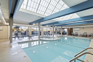 An indoor swimming pool with clear glass walls, a skylight, and lounge chairs. - Bluewater 603 - Direct Gulf Front (Orange Beach)