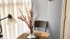 Un coin repas comprenant une table, des chaises, un vase contenant des plantes séchées et deux miroirs muraux.