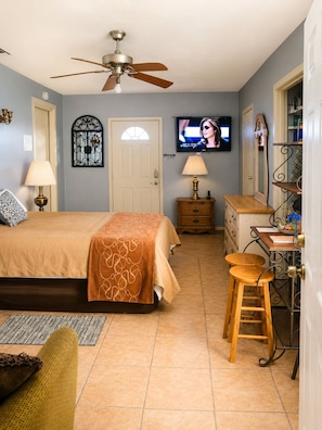 A bedroom with a bed, a desk, a chair, a television, a ceiling fan, and a door. - Cozy Studio Near Lackland AFB/Seaworld (San Antonio)
