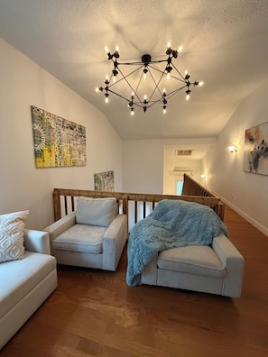 Ein Wohnzimmer mit zwei Sofas, einer Holztreppe und einer Deckenleuchte.