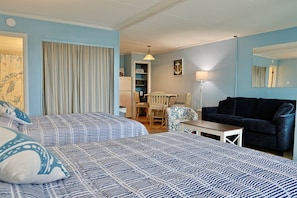 Ein Hotelzimmer mit zwei Betten, einem Sofa, einem Esstisch und einem Sessel.