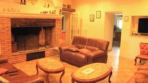 Een woonkamer met een met baksteen beklede open haard, leren banken en houten salontafels.