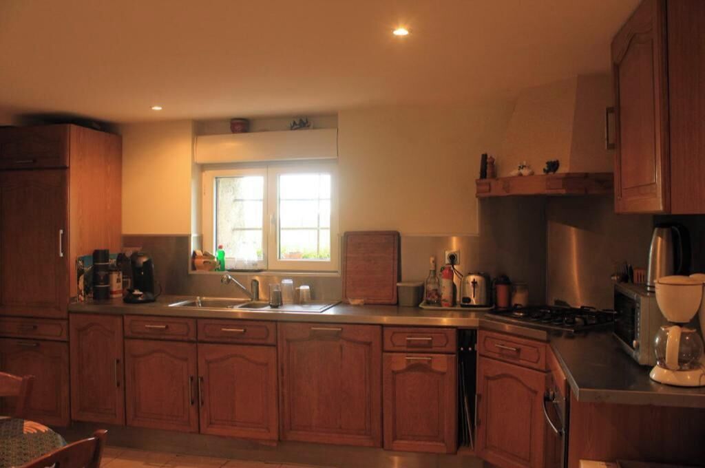 Una cocina con armarios de madera, un fregadero, una ventana y varios electrodomésticos.