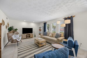 Ein Wohnzimmer mit einer Couch, einem Fernseher, einem Couchtisch und einem Sessel.