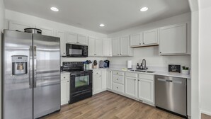 A modern kitchen with white cabinets, stainless steel appliances, a built-in oven, microwave, and dishwasher. - Great for a group! Close and convenient! Fiber high speed internet! (Rock Springs)