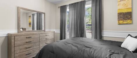 A bedroom with a bed, a dresser, a mirror, and a painting on the wall.