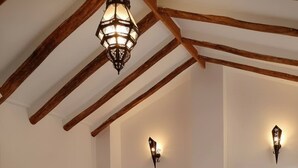 A bedroom with a bed, wooden beams, and wall-mounted lights. - Andalusian Villa - Family Gatherings, Group Retreats & Nature Escapes (Iznajar)