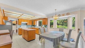 Una cocina amplia con armarios de madera, una isla central y un comedor con mesa y sillas.