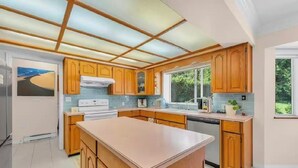 Una cocina moderna con armarios de madera, una isla central y un amplio ventanal que proporciona luz natural.