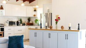 Eine moderne Küche mit weißen Schränken, einem Edelstahlkühlschrank und einer Holzarbeitsplatte.