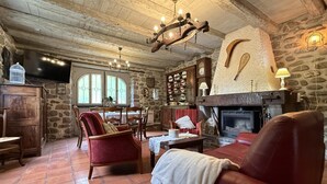 Un interior rústico con paredes de piedra, una chimenea, un comedor y mobiliario de cuero.