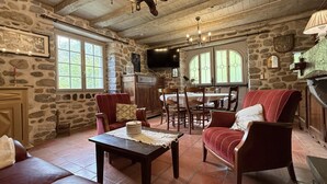 Un interior rústico con paredes de piedra, chimenea, comedor y una acogedora zona de estar.