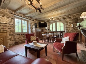 A rustic interior with stone walls, a fireplace, a dining area, and a cozy seating arrangement. - ONDARIA - LICQ ATHEREY (LICQ ATHEREY)