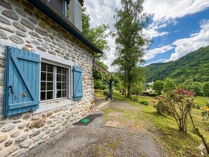 A stone building with blue shutters, a gravel path, and a lush garden with trees and flowers. - ONDARIA - LICQ ATHEREY (LICQ ATHEREY)