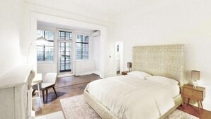 A bedroom with a large bed, a chair, a nightstand, and a window. - Luxury 4-Bedroom UES Townhouse with Private Deck and Garden (New York)
