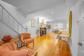 Amplia sala de estar con escalera, suelo de madera y comedor con mesa y sillas.