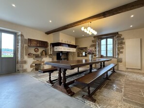 A spacious kitchen with a large island, stone walls, and a rustic ceiling beam. - PURTAUNIA - BEGUIOS - Gîte (BEGUIOS)