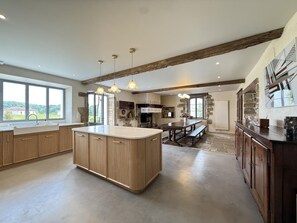 A spacious kitchen with a large island, wooden cabinets, and pendant lighting. - PURTAUNIA - BEGUIOS - Gîte (BEGUIOS)