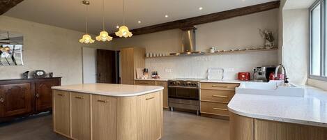 A modern kitchen with a central island, wooden cabinets, stainless steel appliances, and pendant lighting.