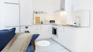 A compact kitchen with white cabinetry, a microwave, a sink, and a stove. - Carine Laguna (San Cristobal de La Laguna)