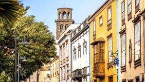 A street with historic buildings, a clock tower, and a street lamp. - Carine Laguna (San Cristobal de La Laguna)
