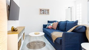 A modern living room with a blue sofa, a round coffee table, and a flat-screen TV mounted on the wall. - Carine Laguna (San Cristobal de La Laguna)