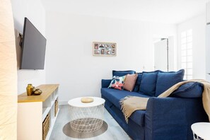 A modern living room with a blue sofa, a round coffee table, and a flat-screen TV mounted on the wall. - Carine Laguna (San Cristobal de La Laguna)