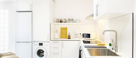 A compact kitchen with a washing machine, a microwave, and a sink.
