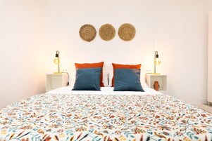 Una cama con una colcha de estampado floral, dos almohadas y dos lámparas de noche.