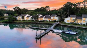 A waterfront property with a dock and boats, surrounded by houses with a lake and trees. - Heron's Rest at Port Villas by Avantstay Waterfront Cove + Dock + Deck Walk to Beach + Sea Pines (Hilton Head Island)