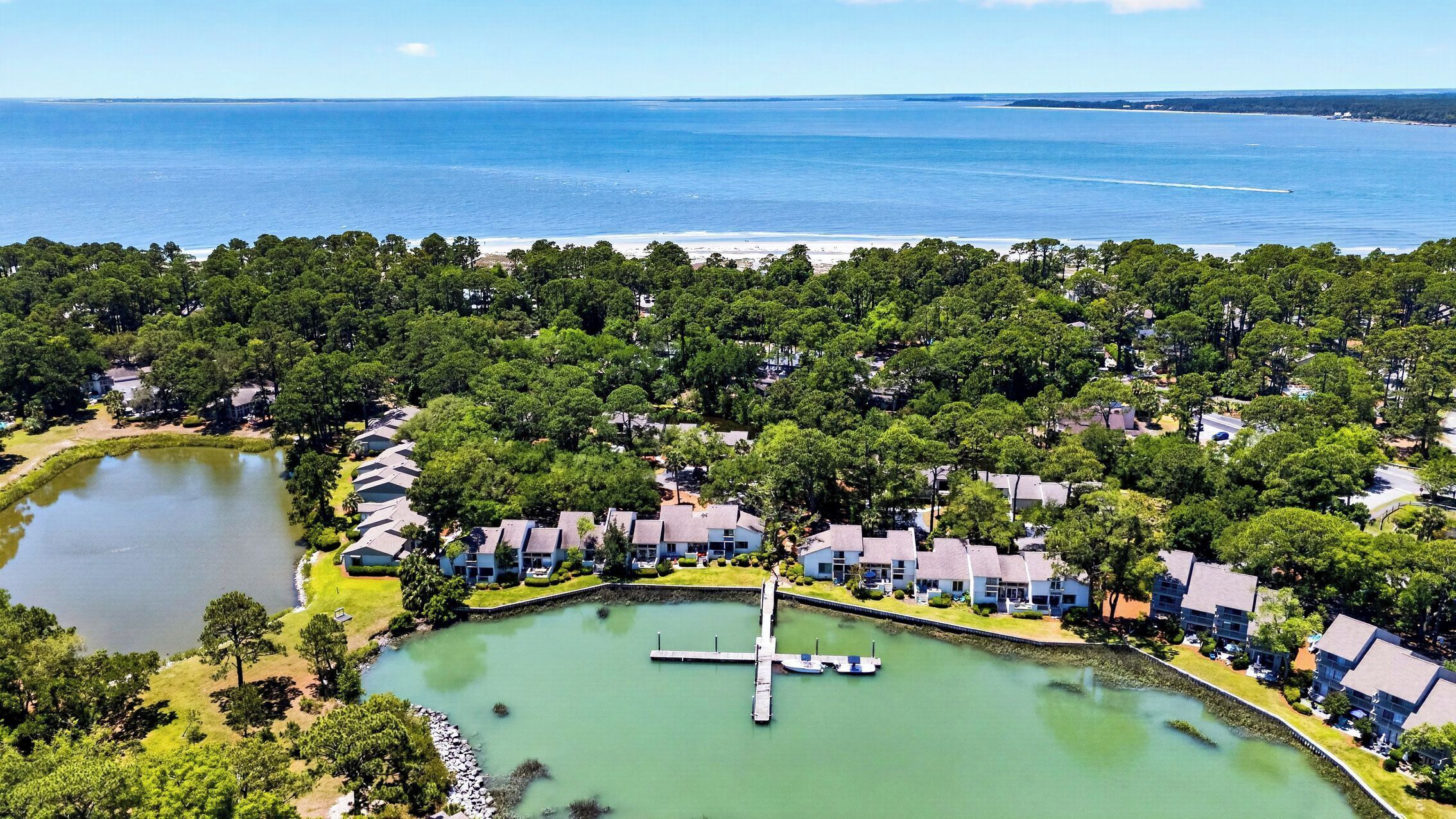 An aerial view of a residential area with houses, a lake, and a pier.